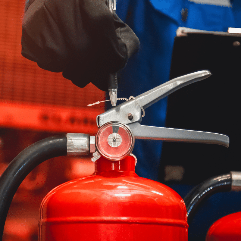 Person inspecting a fire extinguisher.