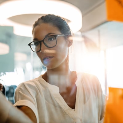 Woman standing at the office behind glass wall with sticky notes