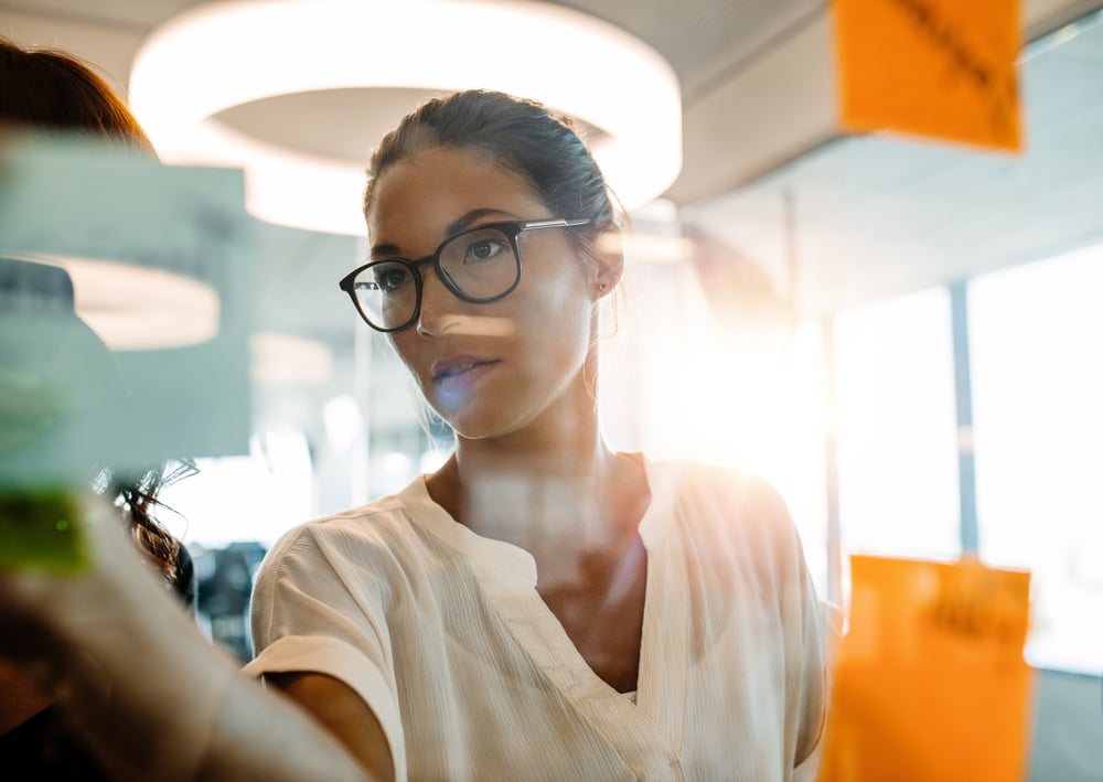 Woman standing at the office behind glass wall with sticky notes