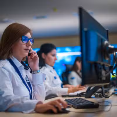 Female guard sitting and monitoring cameras in a surveillance room