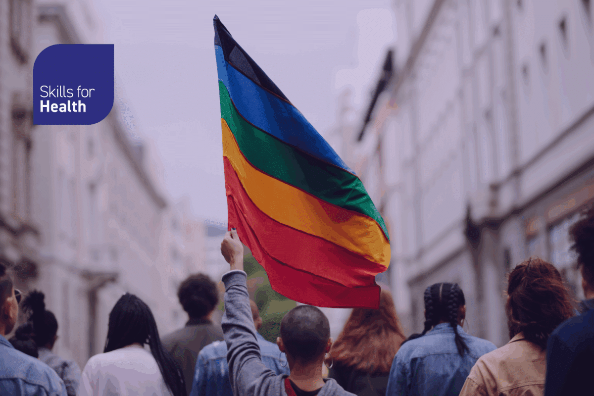 person in pride parade holding LGBTQ+ flag