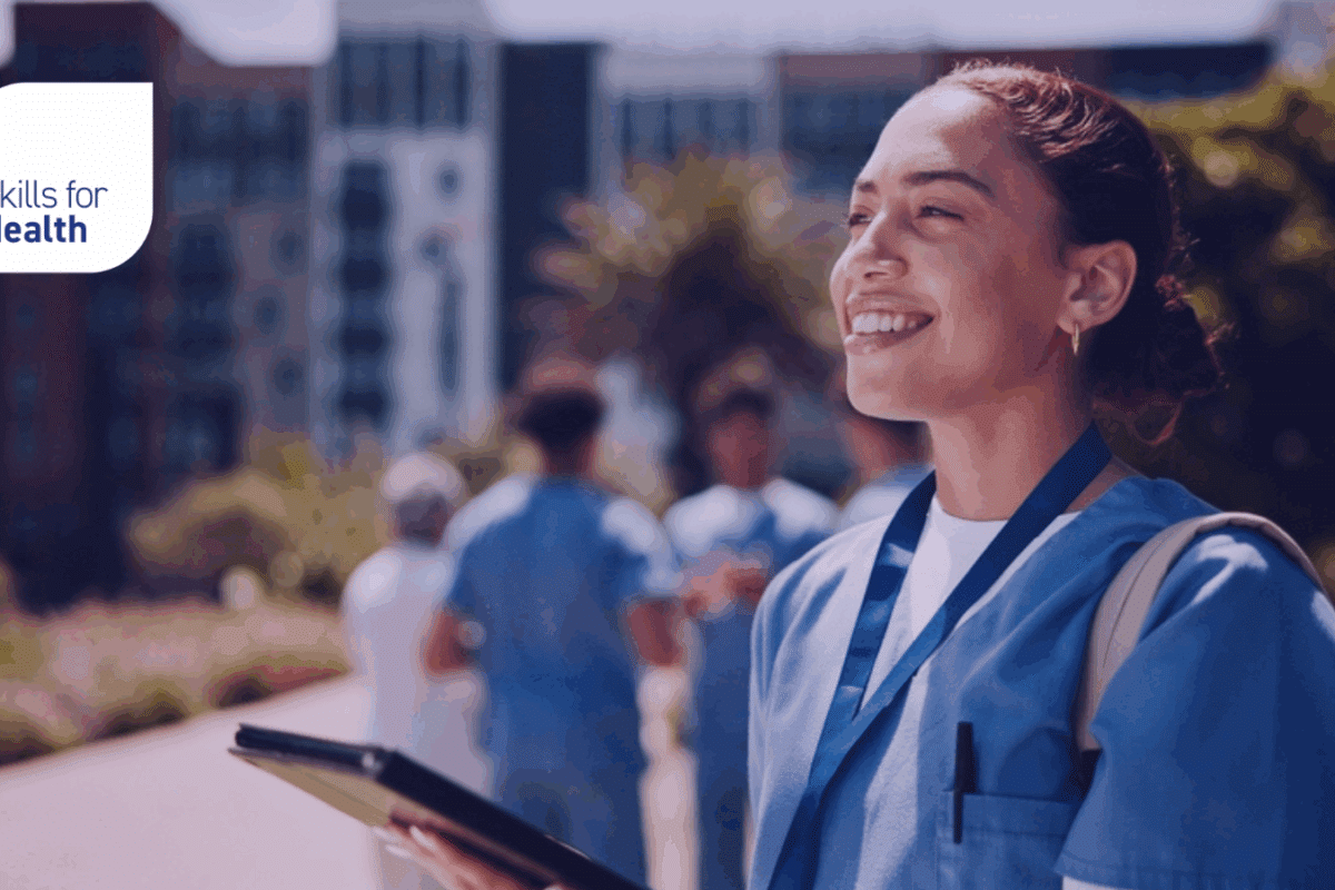 young medical professional stood outside, smiling, looking into the distance
