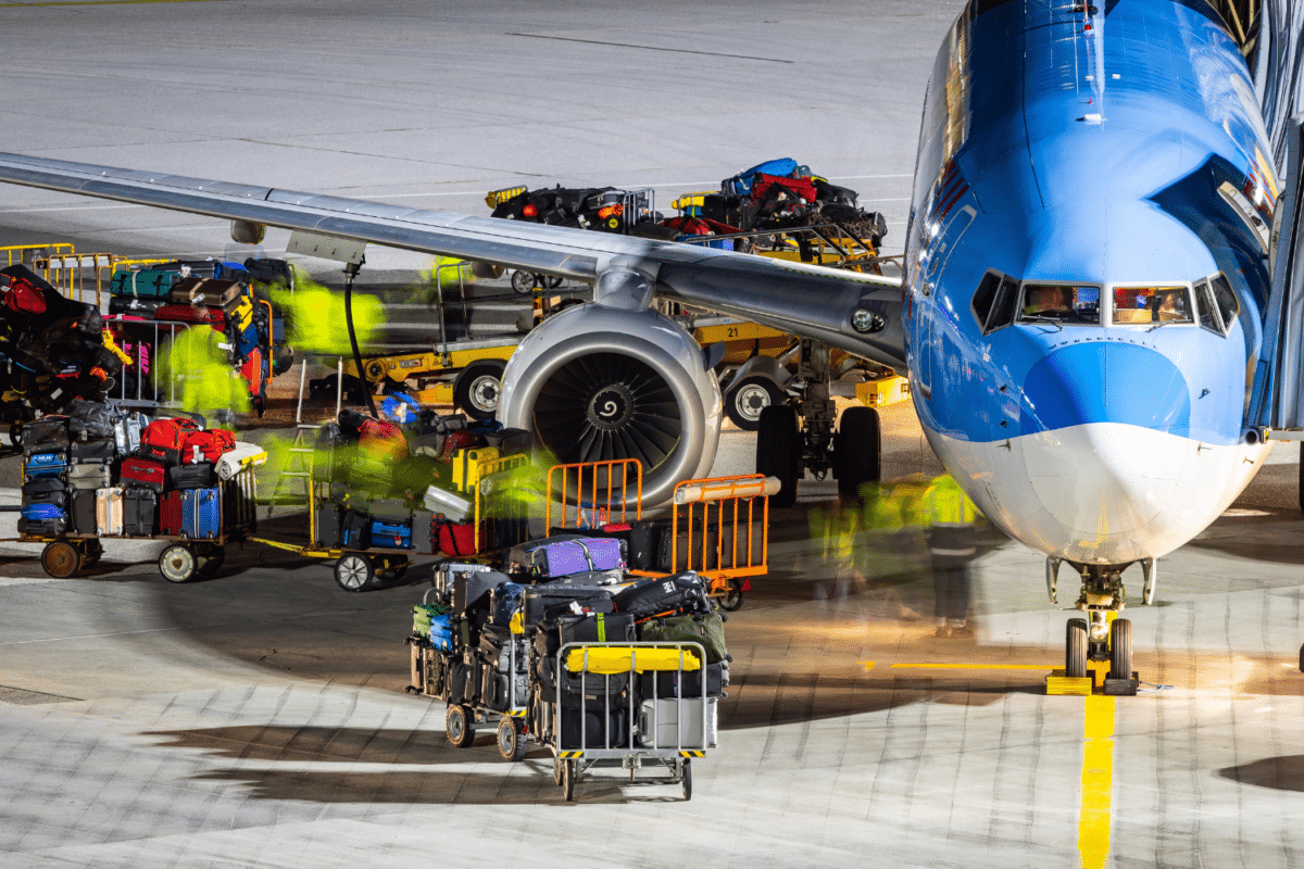 Baggage ground handling on the airport ramp. Workers loading a passenger airplane with lots of baggage and cargo.