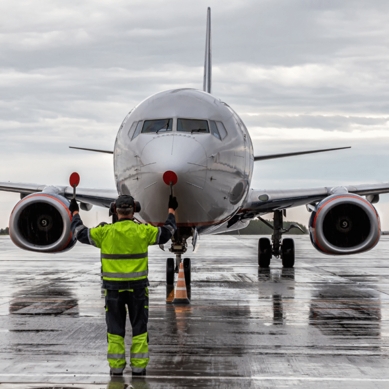Airplane marshalling at the airport apron in rainy weather.