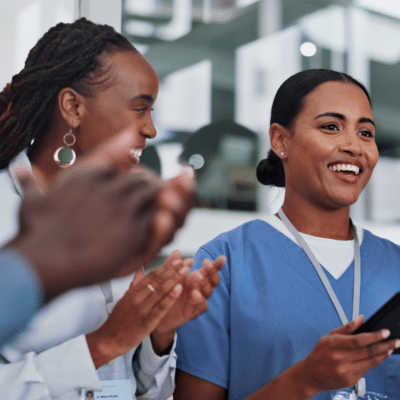 two female medical workers smiling, clapping, celebrating