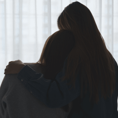 Silhouette image of a woman hugging her friend to comfort