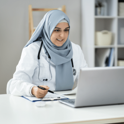 Woman working in a hospital setting looking at a laptop screen
