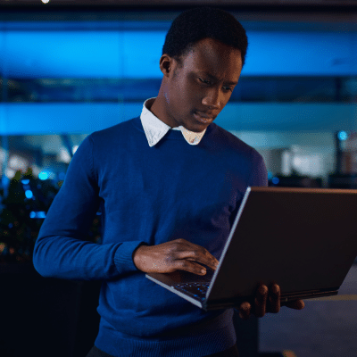Manager stood up works on laptop at night in the office