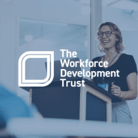 The Workforce Development Trust logo overlayed on an image of someone speaking at a work presentation