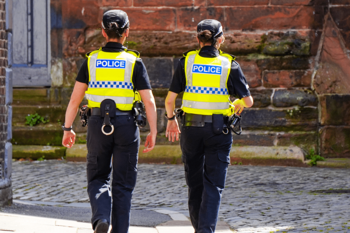 Two female police offices walking down a cobbled street