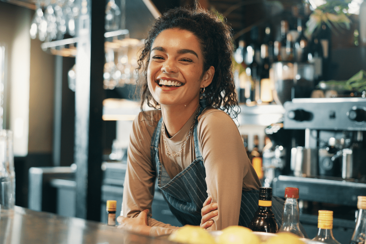 Smiling hospitality worker leaning over a bar